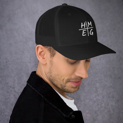 Black HMEG Christian trucker hat with white Heavenly Minded Earthly Good embroidery, shown on a model