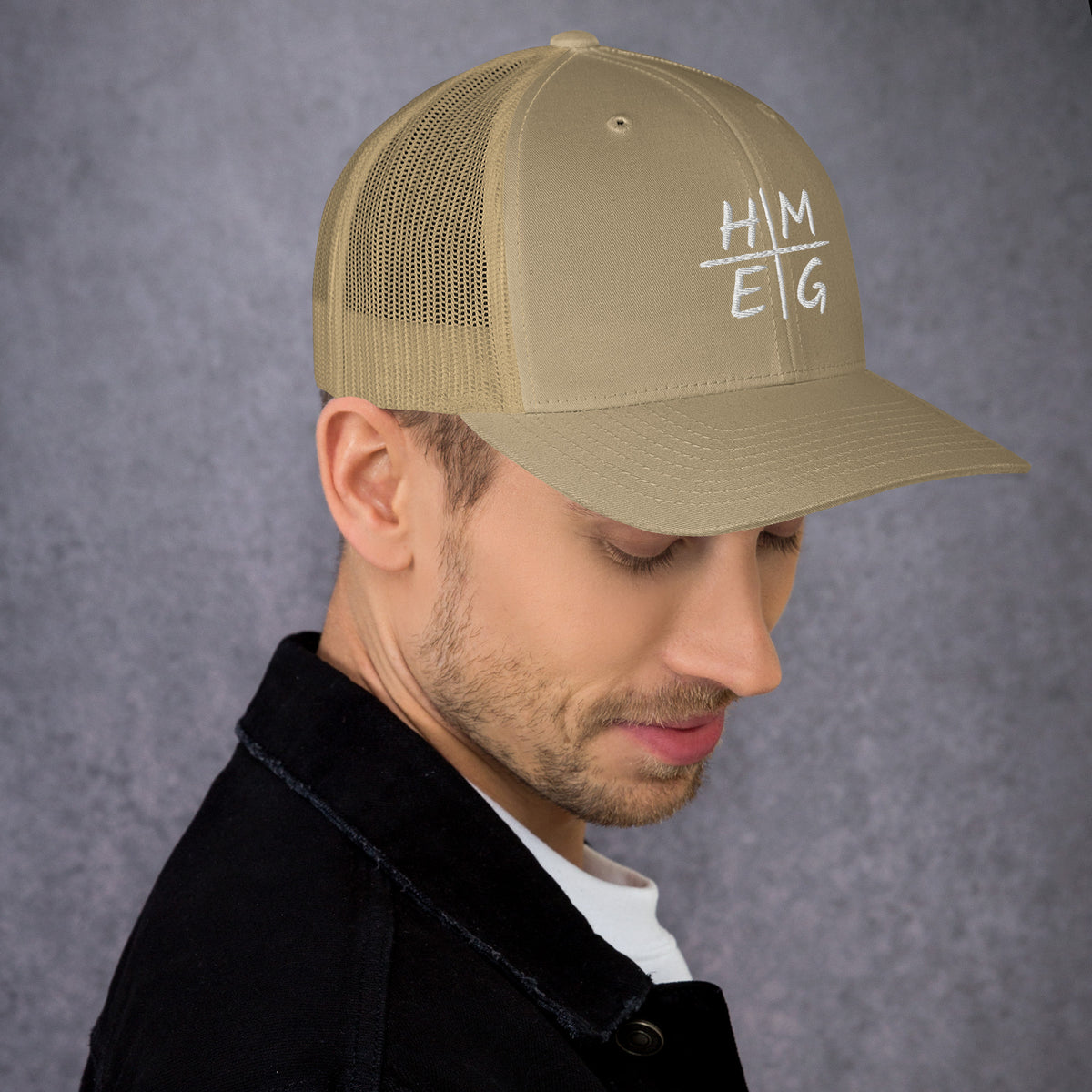 Khaki HMEG embroidered Christian trucker hat shown on a model