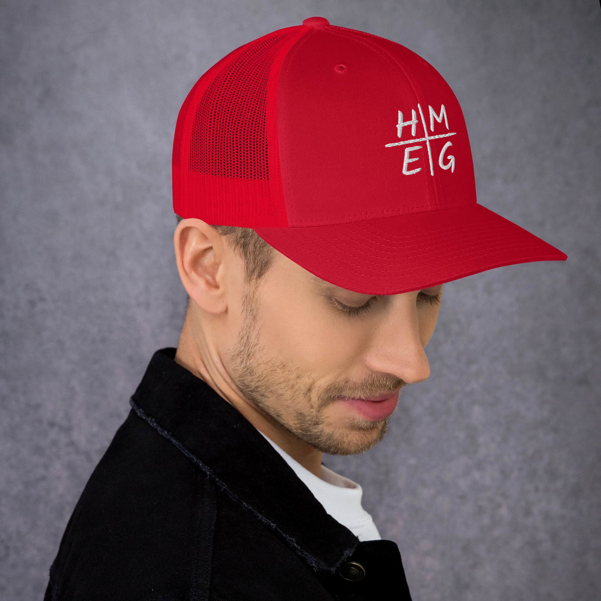 Red HMEG embroidered Christian trucker hat shown at an angle