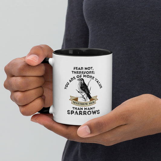 White Sparrow Christian mug with black interior and Matthew 10:31 design, held in two hands right